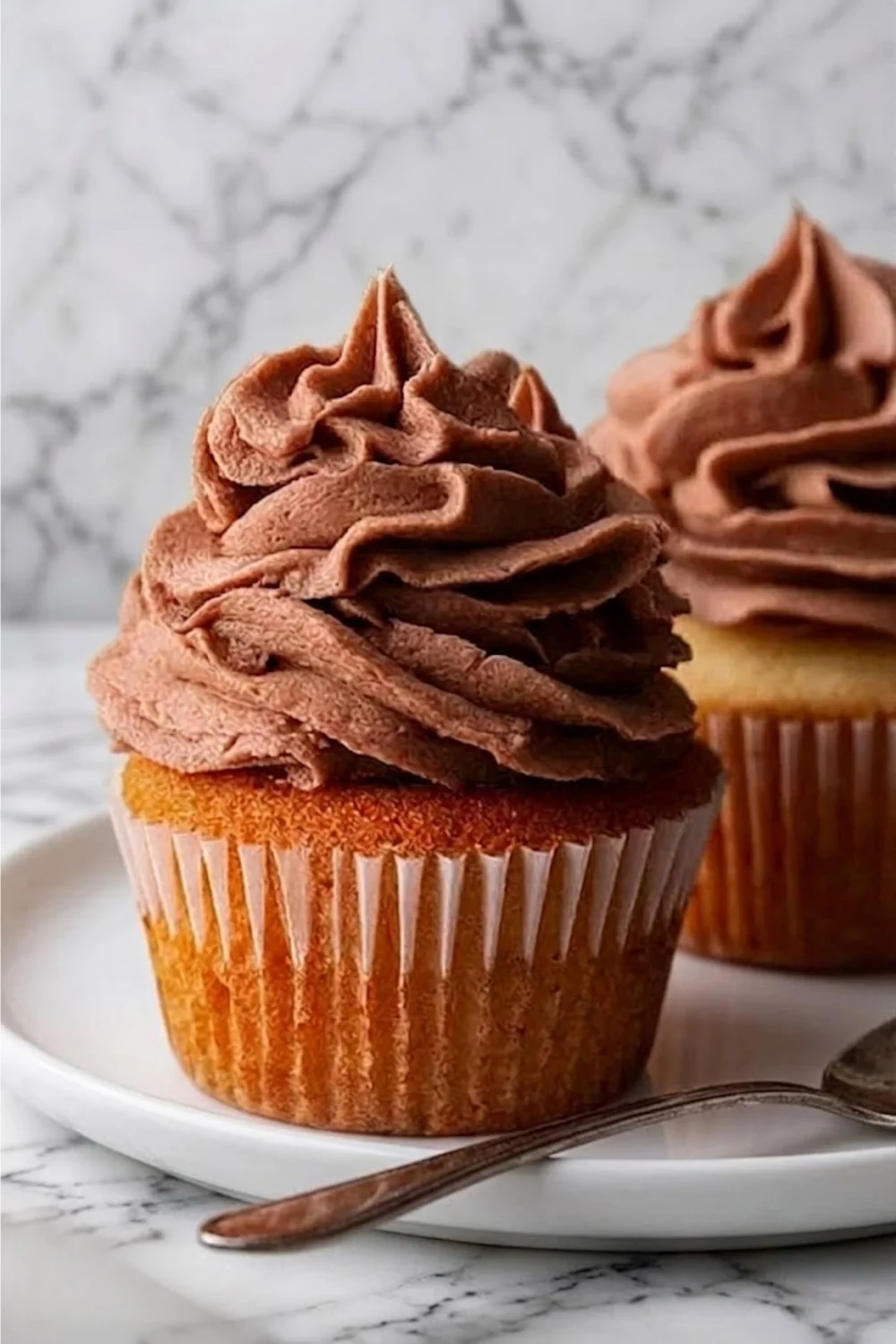 Side view of two cupcakes showing the stable texture and velvety finish of Chocolate Swiss Meringue Buttercream.